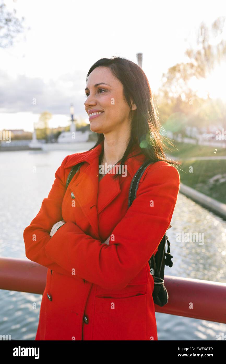 Femme mûre souriante debout avec les bras croisés près de la rivière Banque D'Images