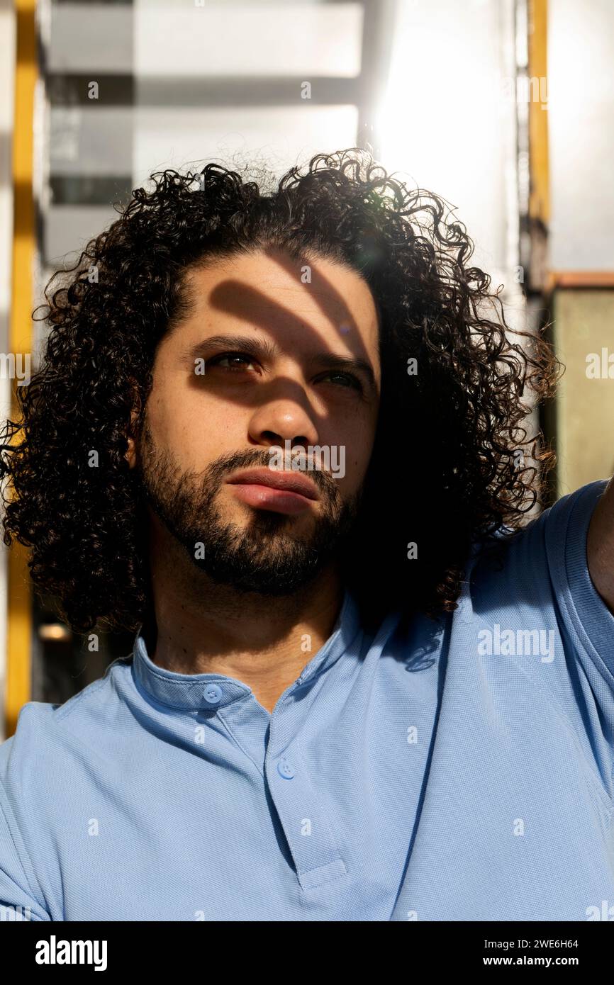 Homme aux cheveux bouclés portant un polo bleu Banque D'Images