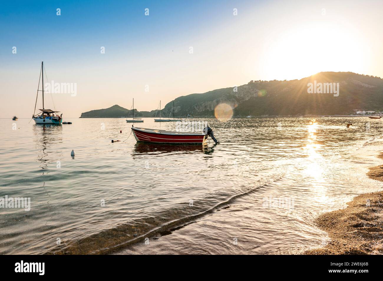 Grèce, Îles Ioniennes, Agios Georgios, Bateaux devant la plage Agios Georgios Pagon au coucher du soleil Banque D'Images