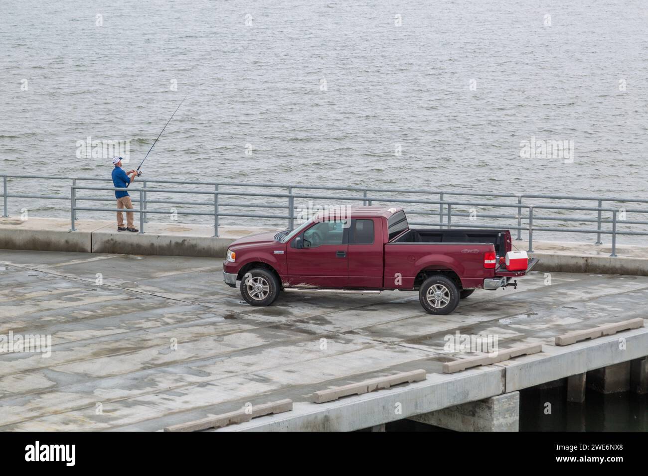 Homme pêchant de la jetée de pêche à côté de sa camionnette rouge Ford F150 à Pass Christian, Mississippi Banque D'Images