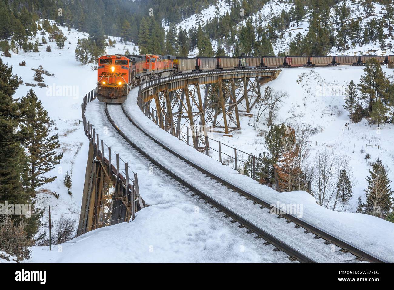 le train transportant des wagons à charbon vers mullan passe au-dessus d'un chevalet en hiver près d'austin, montana Banque D'Images