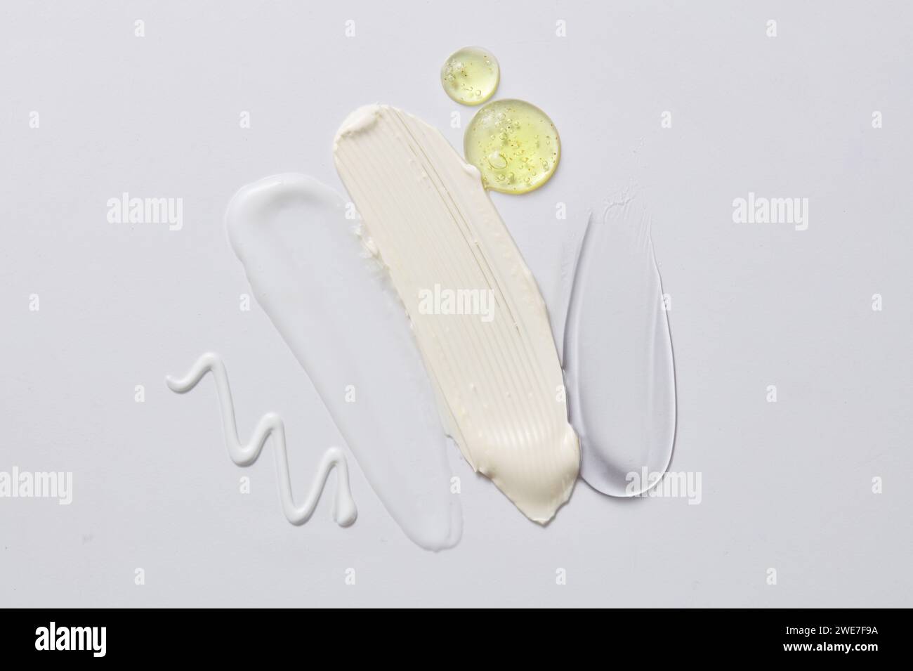 Concept naturel de soins de la peau de gouttes de sérum de couleur jaune et quelques frottis de texture cosmétique. Tache cosmétique sur fond clair gros plan Banque D'Images