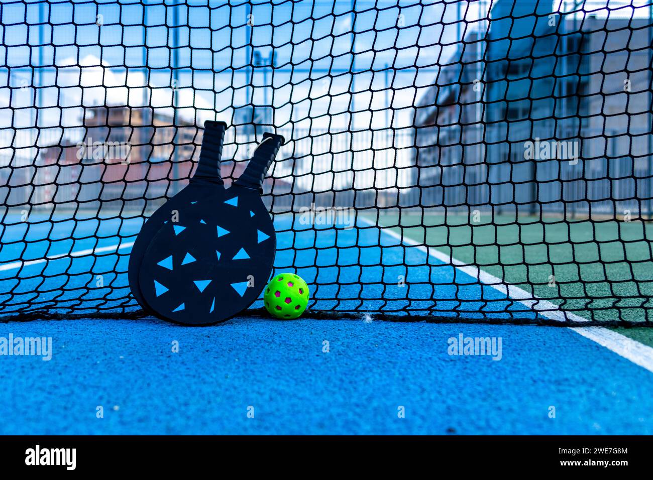 Boule de pickleball et pagaies reposant sur le filet d'un terrain de pickleball Banque D'Images