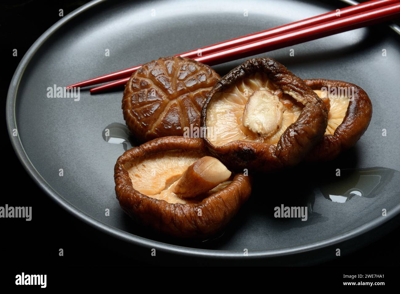 Champignons shiitake séchés et trempés sur une assiette avec des baguettes Banque D'Images