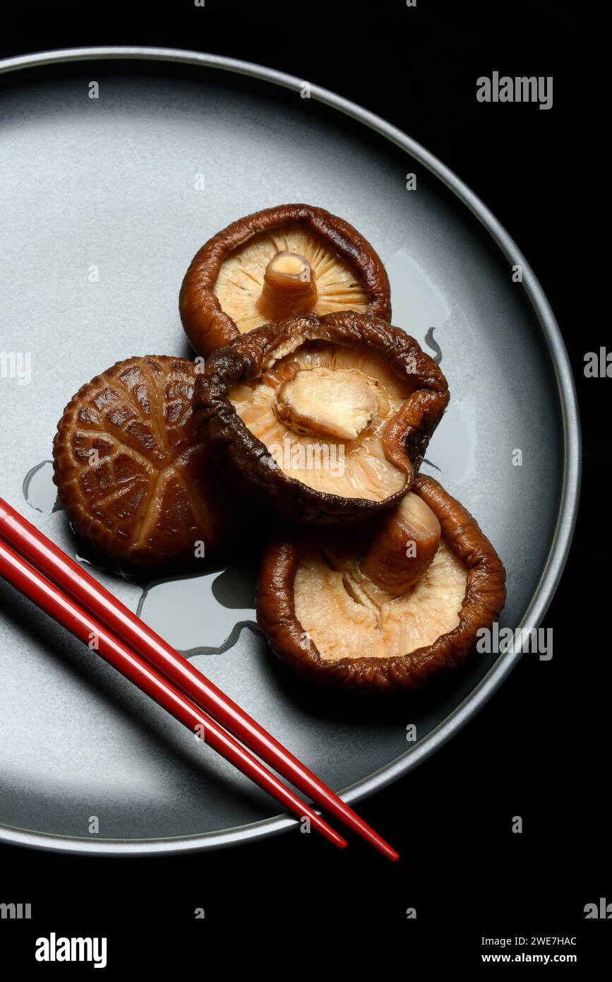Champignons shiitake séchés et trempés sur une assiette avec des baguettes Banque D'Images