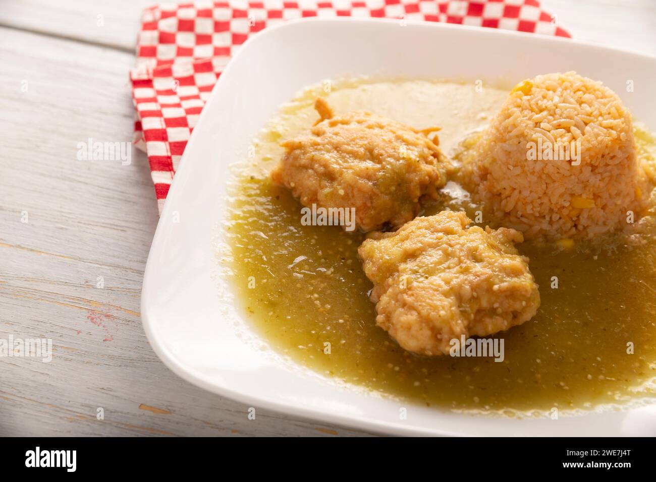 Côtelettes de viande de poulet râpée frites dans un œuf en pâte, au Mexique connu sous le nom de Tortitas de Pollo, baignées de sauce verte et accompagnées de riz. Tradition Banque D'Images