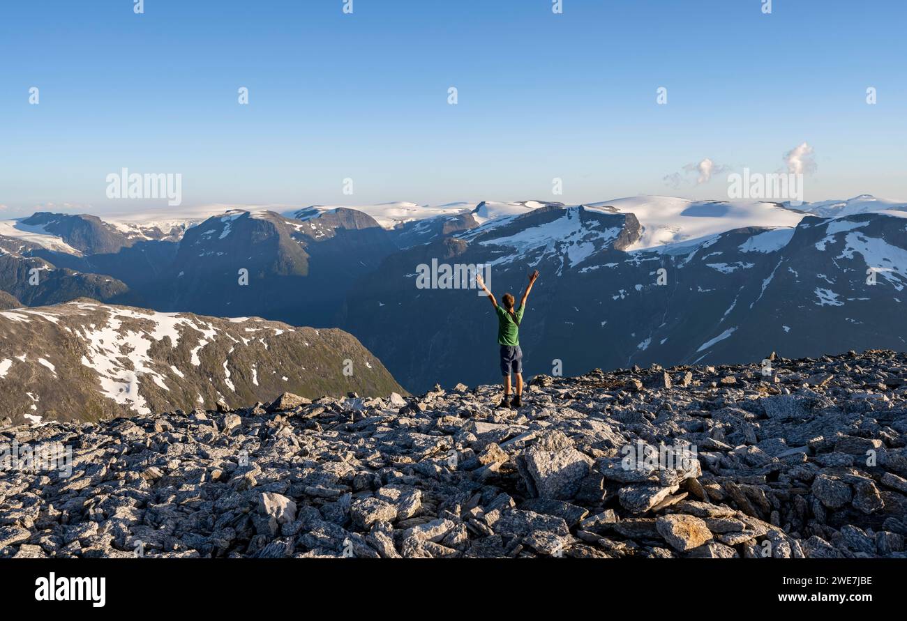 Panorama de montagne avec des sommets montagneux et le glacier Jostedalsbreen, alpiniste tend les bras dans les airs, au sommet de Skala, Loen, Norvège Banque D'Images