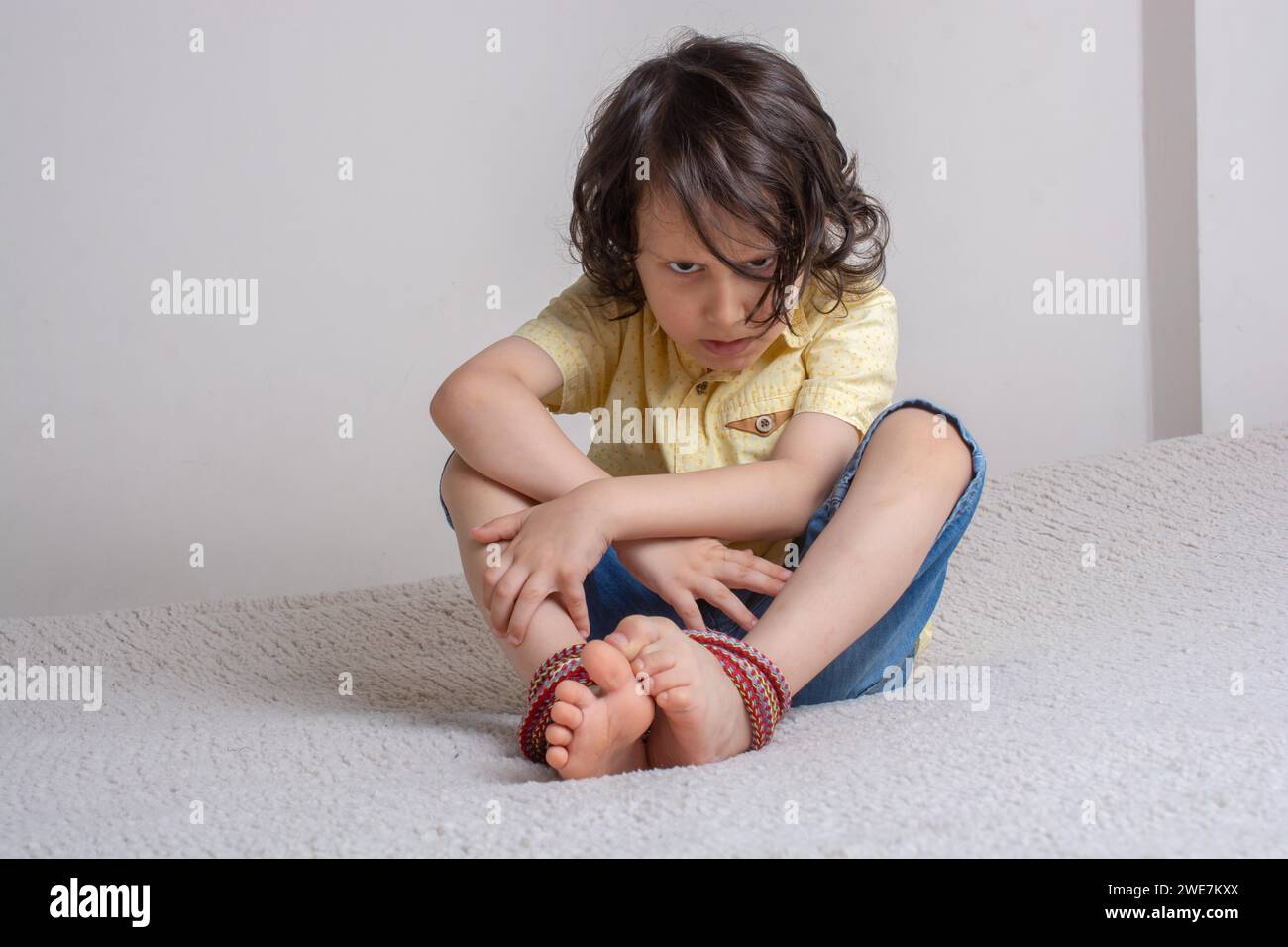 Petit garçon aux Pieds attaché avec corde dans le stress émotionnel Banque D'Images