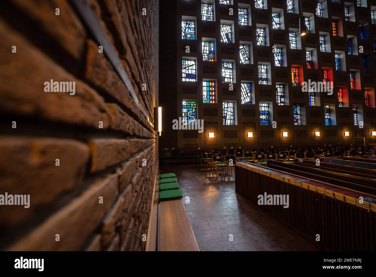 Vue intérieure d'une église avec accent sur la texture du mur de briques et des fenêtres colorées, Pforzheim, Allemagne Banque D'Images