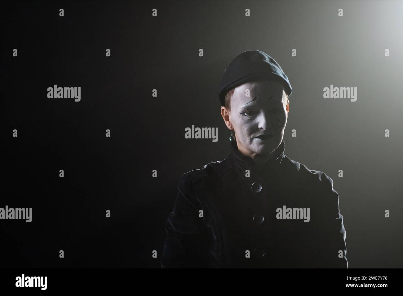 Portrait minimal de triste mime debout sur scène dans l'éclairage de contour sur fond noir, espace de copie Banque D'Images