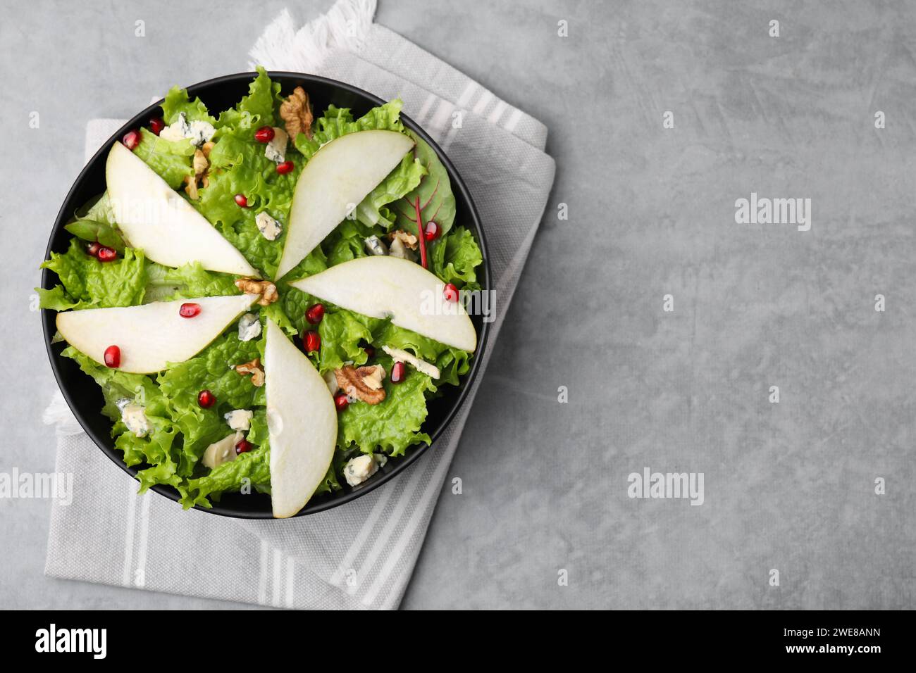 Délicieuse salade de poires dans un bol sur une table texturée grise, vue de dessus. Espace pour le texte Banque D'Images