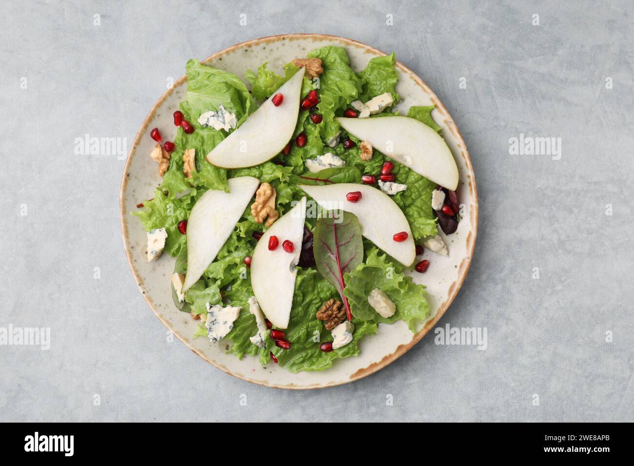Assiette avec une délicieuse salade de poires sur une table texturée grise, vue de dessus Banque D'Images