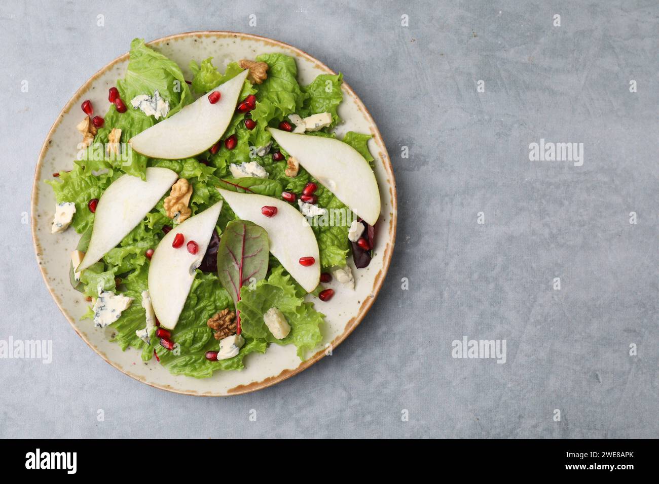 Assiette avec une délicieuse salade de poires sur une table texturée grise, vue de dessus. Espace pour le texte Banque D'Images