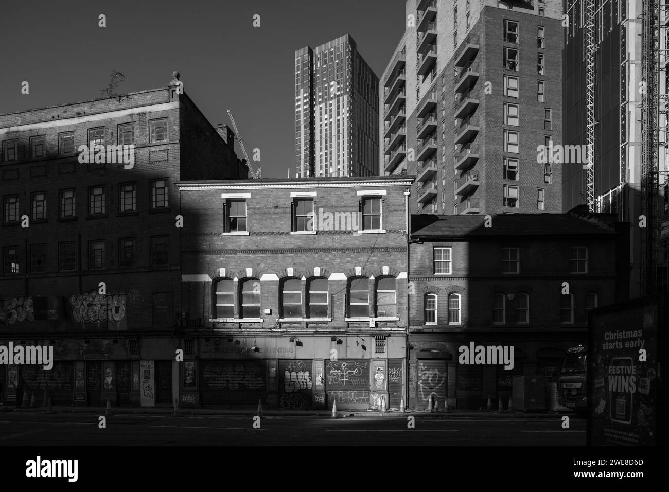 Prise de Chapel Street, Salford, Royaume-Uni regardant les magasins de briques délabrés avec la tour résidentielle de luxe contrastée de Cortland en arrière-plan Banque D'Images