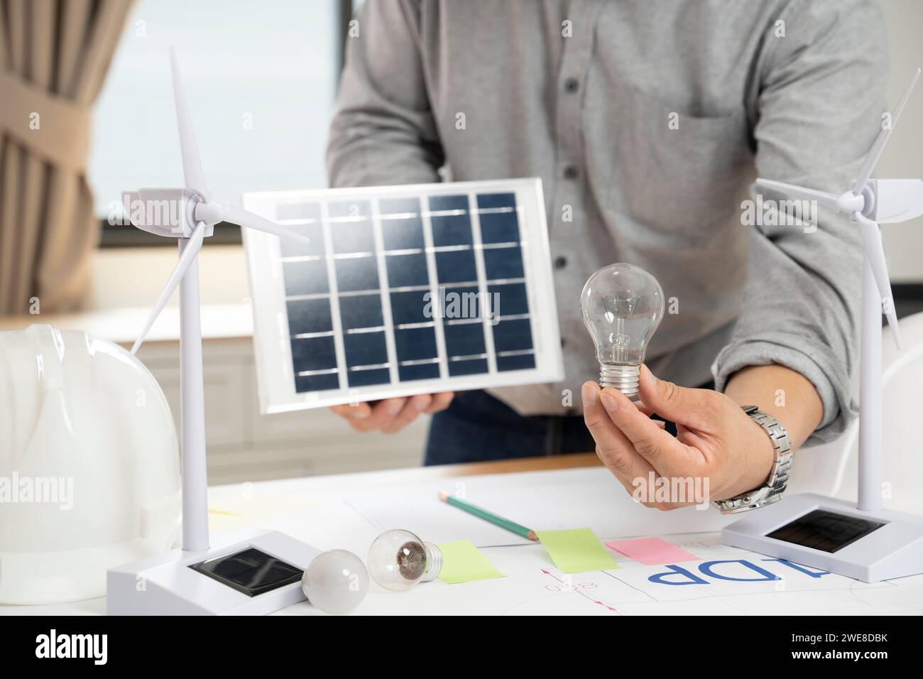 Homme d'affaires tenant des panneaux solaires et des ampoules au bureau. Banque D'Images