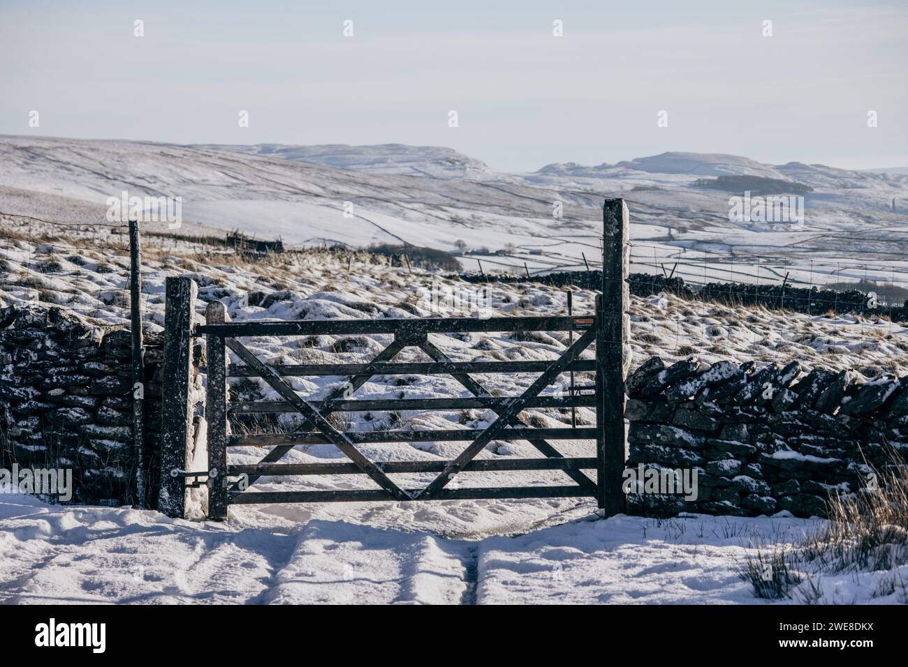 Une porte dans un mur de pierres sèches dans les Yorkshire Dales en Angleterre. Pris sur une belle journée d'hiver avec beaucoup de neige et des vues lointaines de collines ondulantes. Banque D'Images