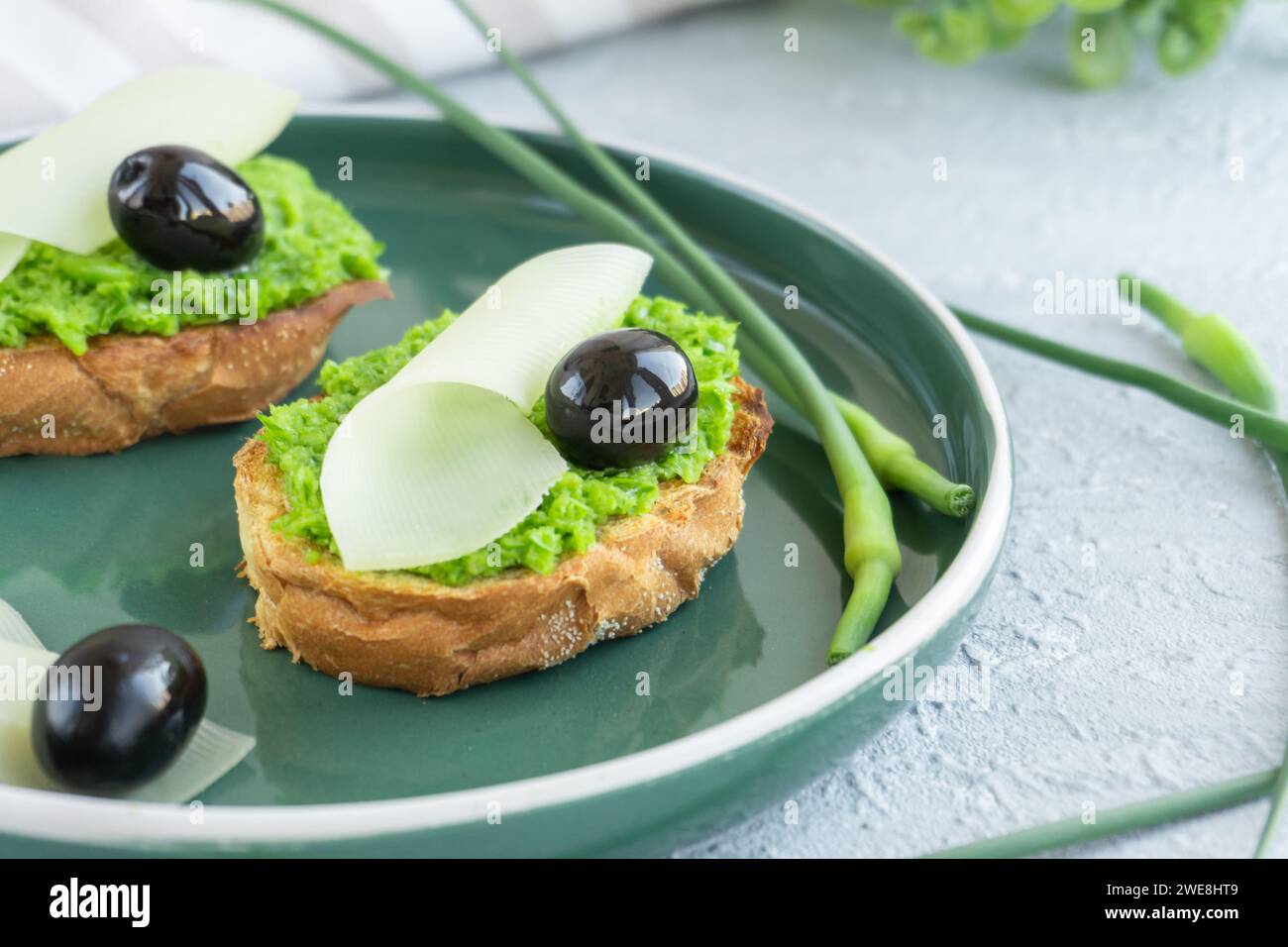 Pain à l'ail. Tranches de baguette avec beurre à l'ail, olives, fromage et flèches à l'ail dans une assiette verte Banque D'Images