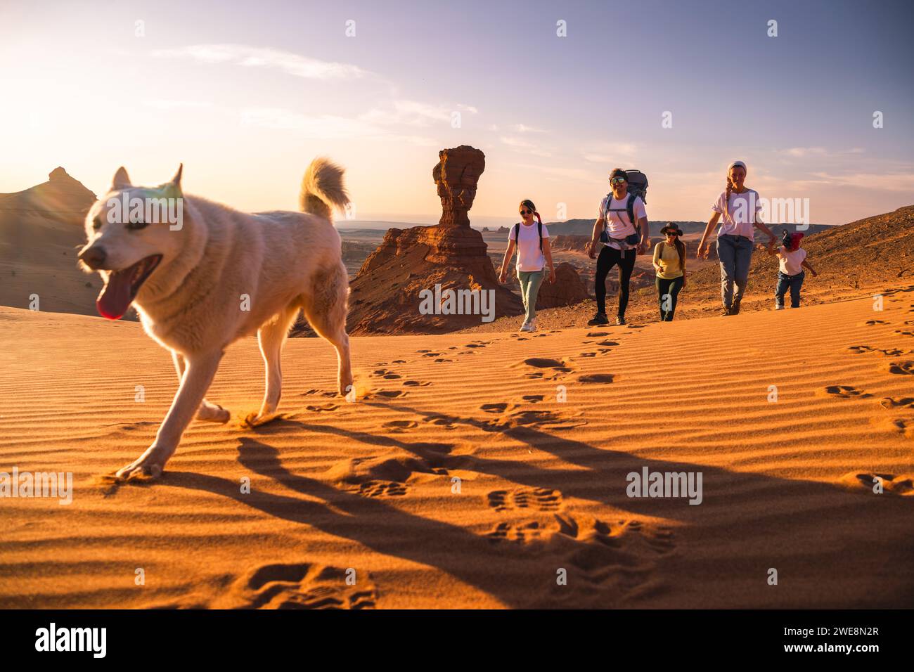 Grand père de famille, mère et petites filles marche avec chien blanc dans le désert de Gobi Banque D'Images