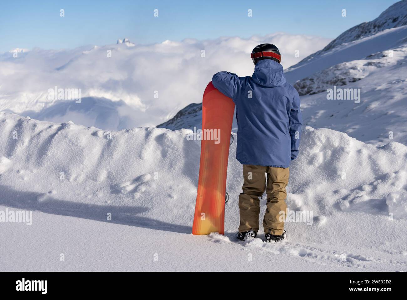 L'homme tient un snowboard sur le fond des alpes. Hiver dans les alpes françaises. Snowboarder stands avec un snowboard dans les alpes. Banque D'Images
