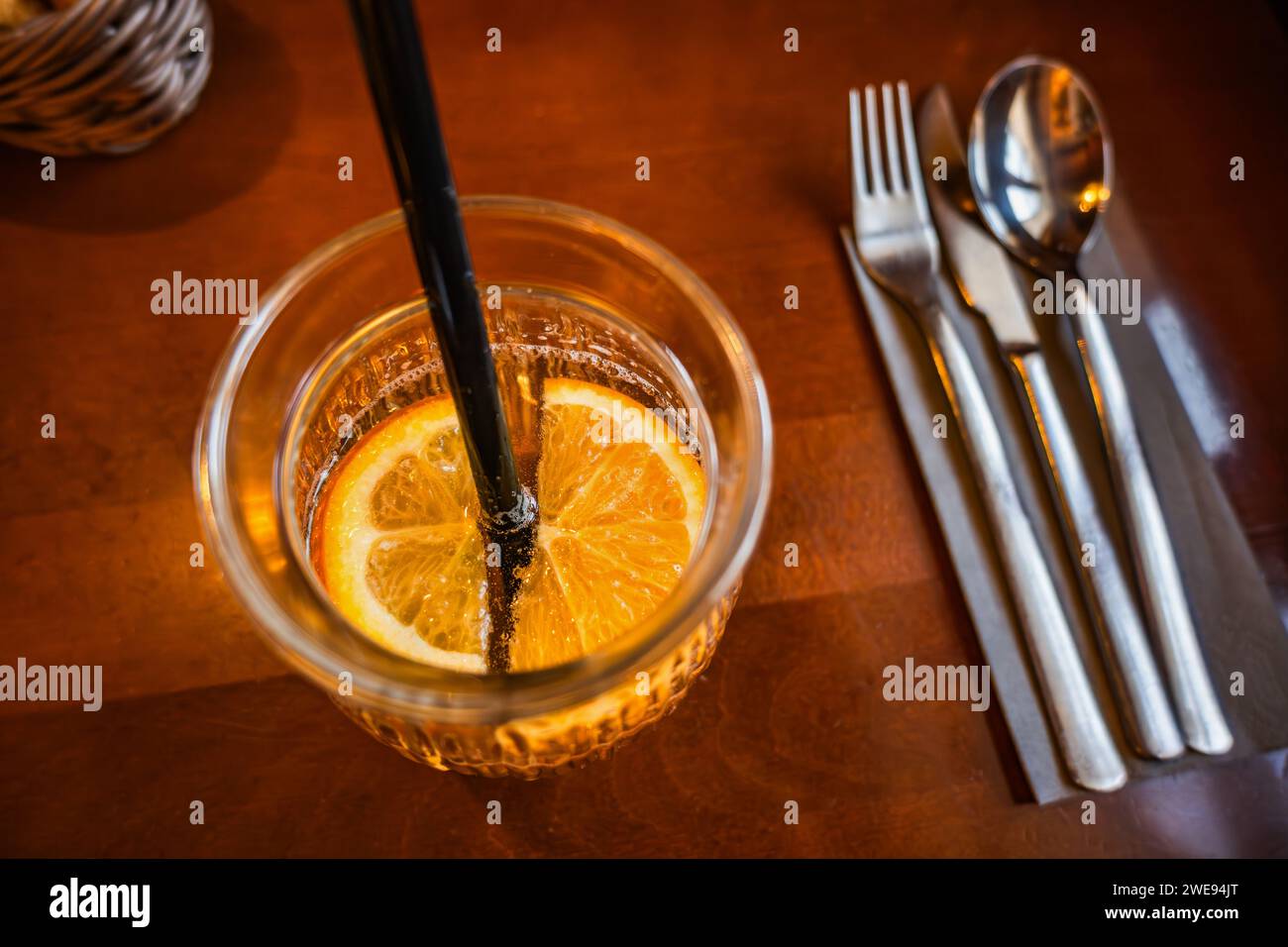 Boisson fruitée avec des tranches d'orange en verre avec de la paille, des couverts. Gros plan sur la table du restaurant, vue de dessus. Banque D'Images Boisson fruitée avec des tranches d'orange en verre avec de la paille, des couverts. Gros plan sur la table du restaurant, vue de dessus. Banque D'Images