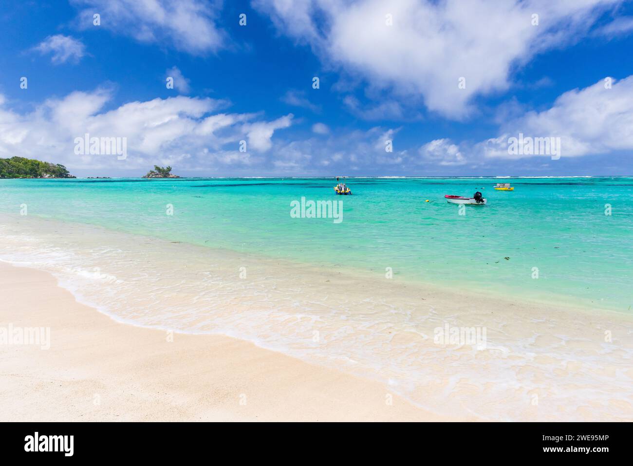 Plage d'Anse Royale, Seychelles. Vue côtière avec de petits bateaux à moteur sous ciel bleu avec des nuages blancs par une journée ensoleillée Banque D'Images