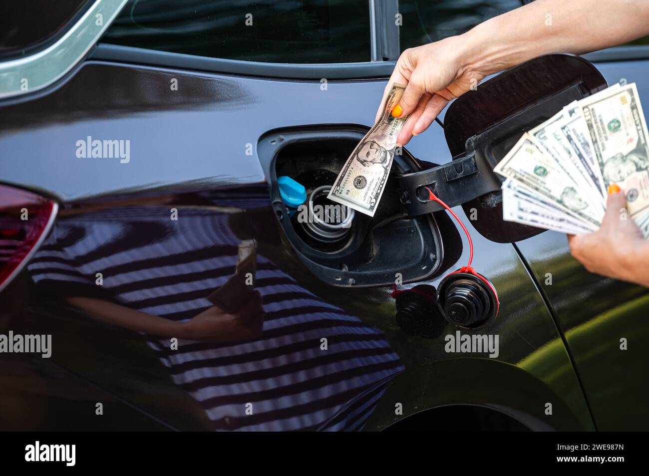 main de femme qui met l'argent dans le réservoir de voiture, gros plan, concept de carburant coûteux, crise de carburant Banque D'Images