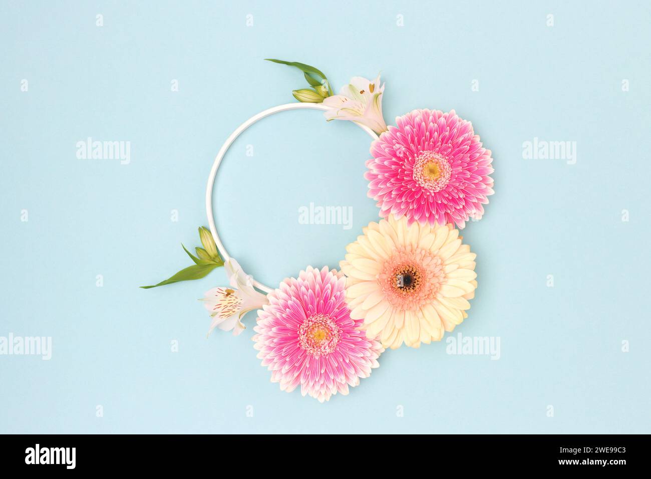 Couronne faite de feuilles vertes, alstroemeria et fleurs de gerbera sur un fond bleu. Banque D'Images