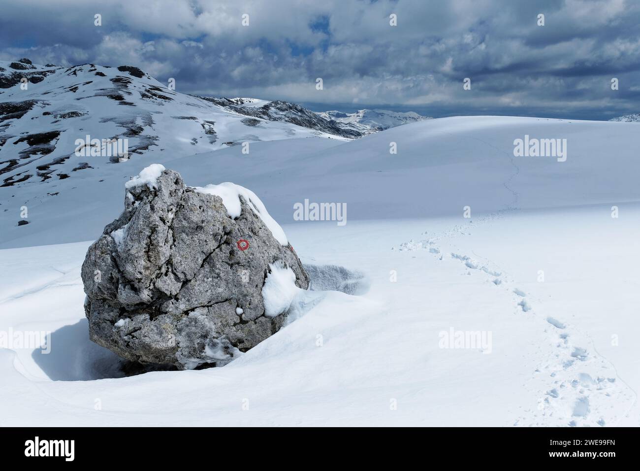 Marqueur de sentier de randonnée dans les montagnes en hiver. Pas laissés par un alpiniste. Paysage blanc enneigé. Marque rouge et blanche pour suivre le chemin. Banque D'Images