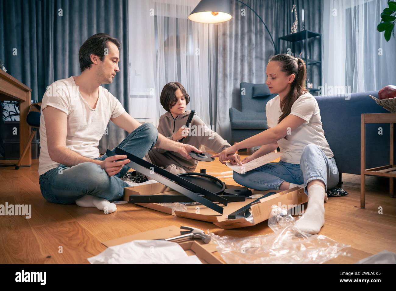 Les parents avec un enfant assemblent de nouveaux meubles à partir de pièces pour l'auto-assemblage. Banque D'Images