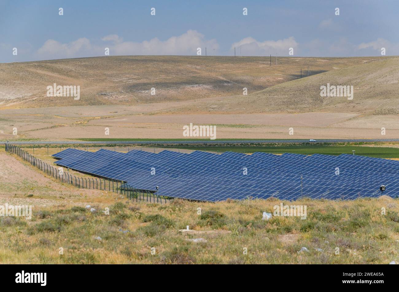 Panneaux solaires dans une rangée à une ferme d'énergie renouvelable dans un champ herbacé sec avec des collines en arrière-plan, pris dans l'est de la Turquie Banque D'Images