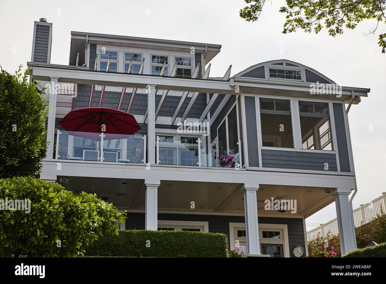 Maison de plage moderne avec parapluie rouge et fleurs roses Banque D'Images