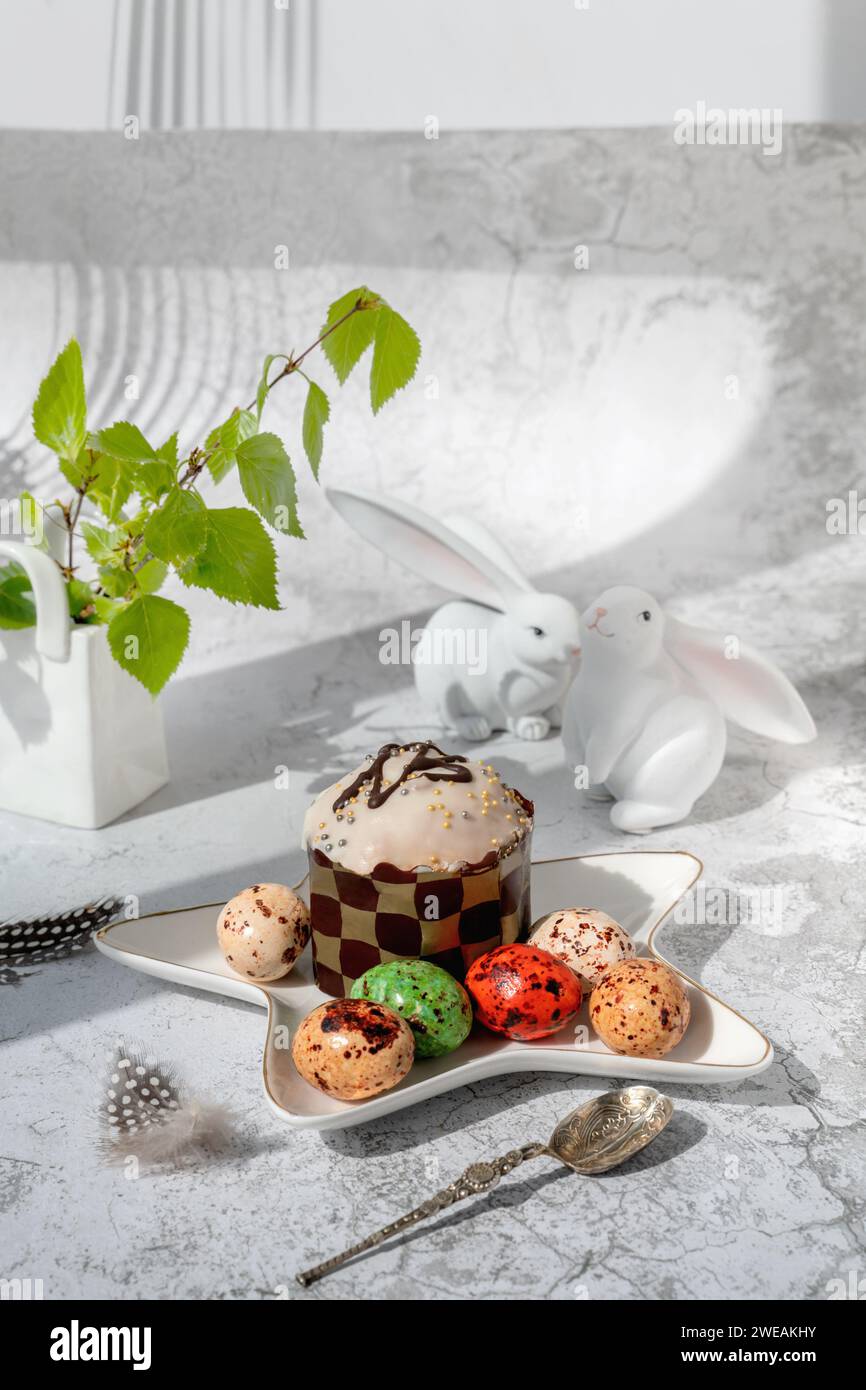 Décor de Pâques. Nature morte de Pâques avec des gâteaux de Pâques colorés, des œufs sur une assiette à dessert de lapin. Régal de Pâques traditionnel sur la table de fête décorée avec spr Banque D'Images
