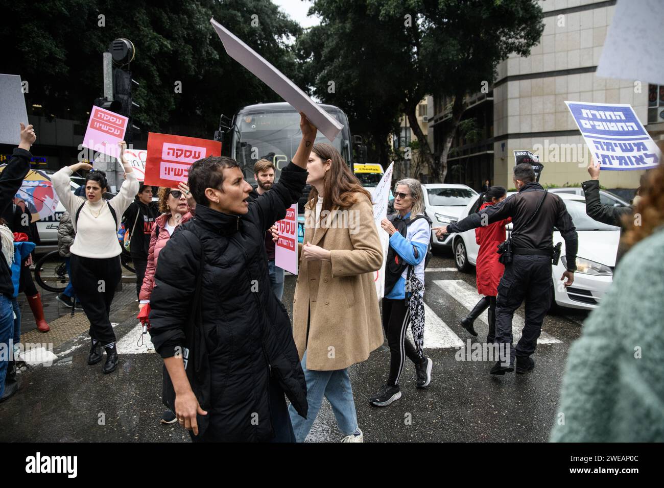 Tel Aviv, Israël. 24 janvier 2024. Un officier de police israélien tente de dégager la route pour empêcher les femmes israéliennes de protester contre un carrefour en demandant un accord immédiat sur les otages et un cessez-le-feu. 136 otages israéliens sont toujours détenus en captivité par le Hamas à Gaza, dans des conditions potentiellement mortelles depuis l'attaque du 7 octobre. Crédit : SOPA Images Limited/Alamy Live News Banque D'Images