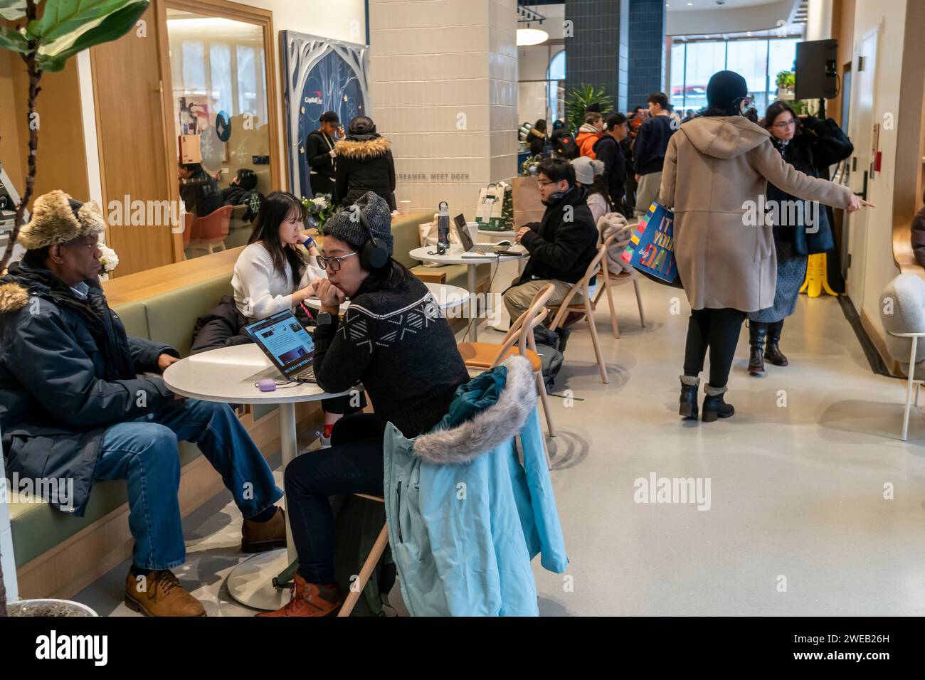 Les clients et les clients potentiels célèbrent l’ouverture officielle d’une succursale du Capital One Cafe à Herald Square à New York le samedi 20 janvier 2024. En plus d'avoir une succursale de la banque enterrée à l'intérieur, le café accueillant sert de la nourriture et des boissons et sert d'espace de co-working, que vous soyez client ou non. (© Richard B. Levine) Banque D'Images