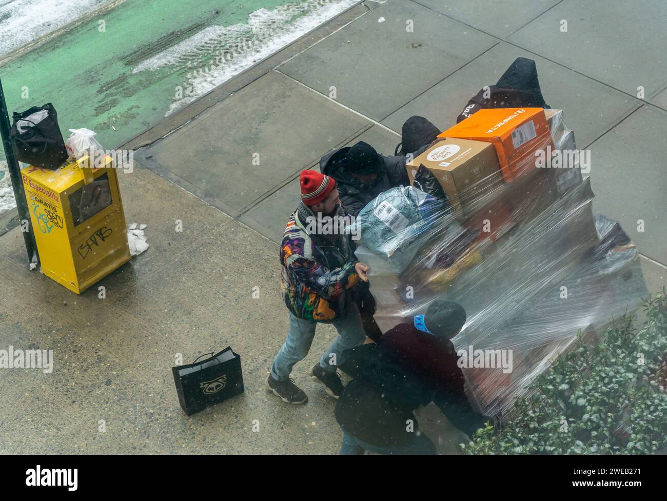 Un travailleur d’Amazon fait appel à l’aide d’un passant pour redresser son chariot renversé devant un immeuble d’appartements à New York le vendredi 19 janvier 2024. (© Richard B. Levine) Banque D'Images