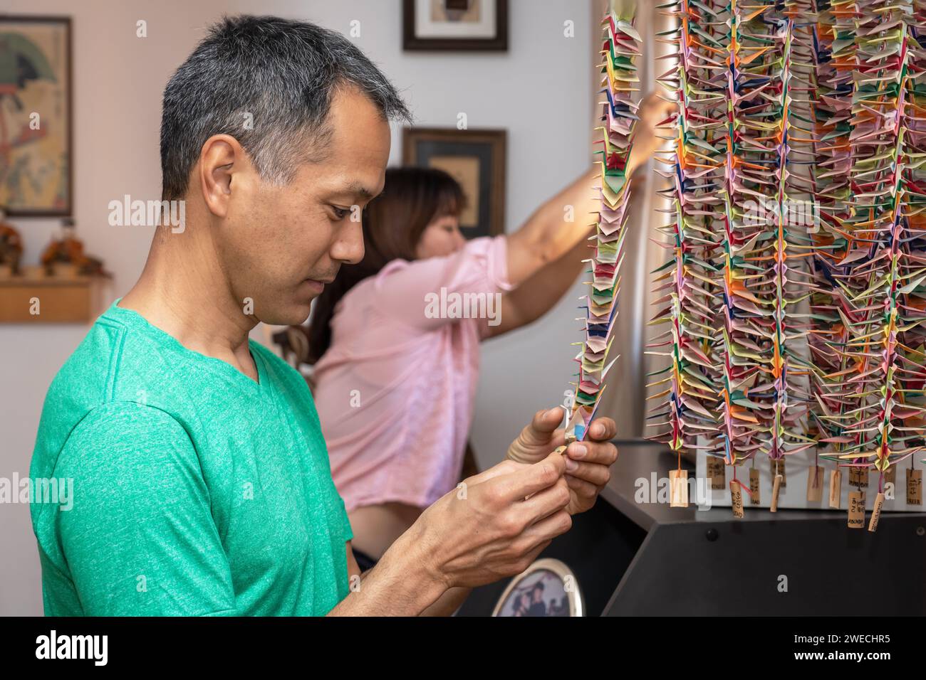 Homme japonais tenant une grue à papier. Souvenirs dans la maison familiale Banque D'Images
