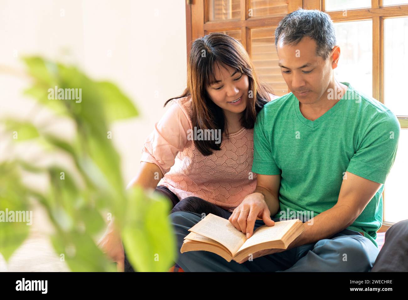 Deux étudiants japonais, hommes et femmes, lisant un livre. Jeune couple asiatique lisant un livre à la maison. Banque D'Images