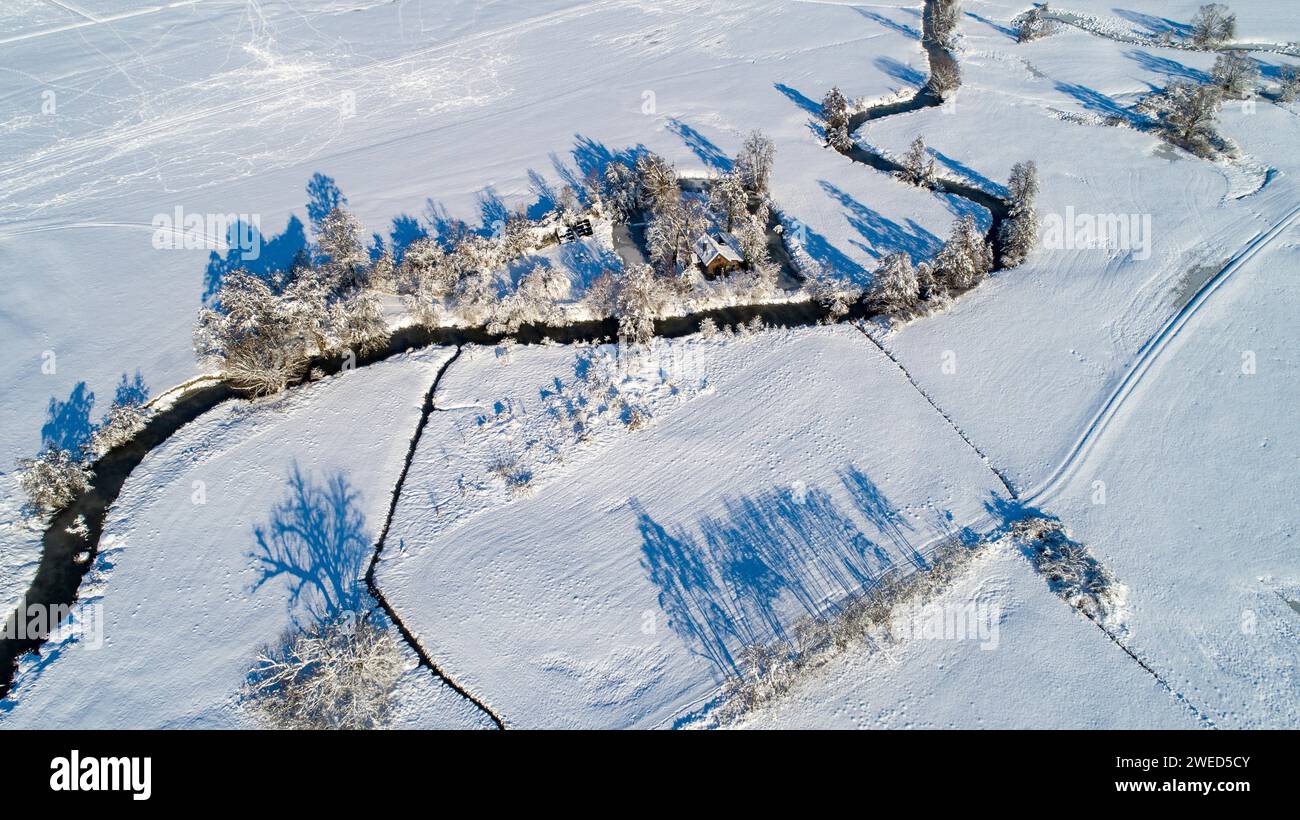 Drone shot de la rivière Schmutter serpentant naturellement à travers le paysage hivernal enneigé du parc naturel Western Forests près d'Augsbourg Banque D'Images