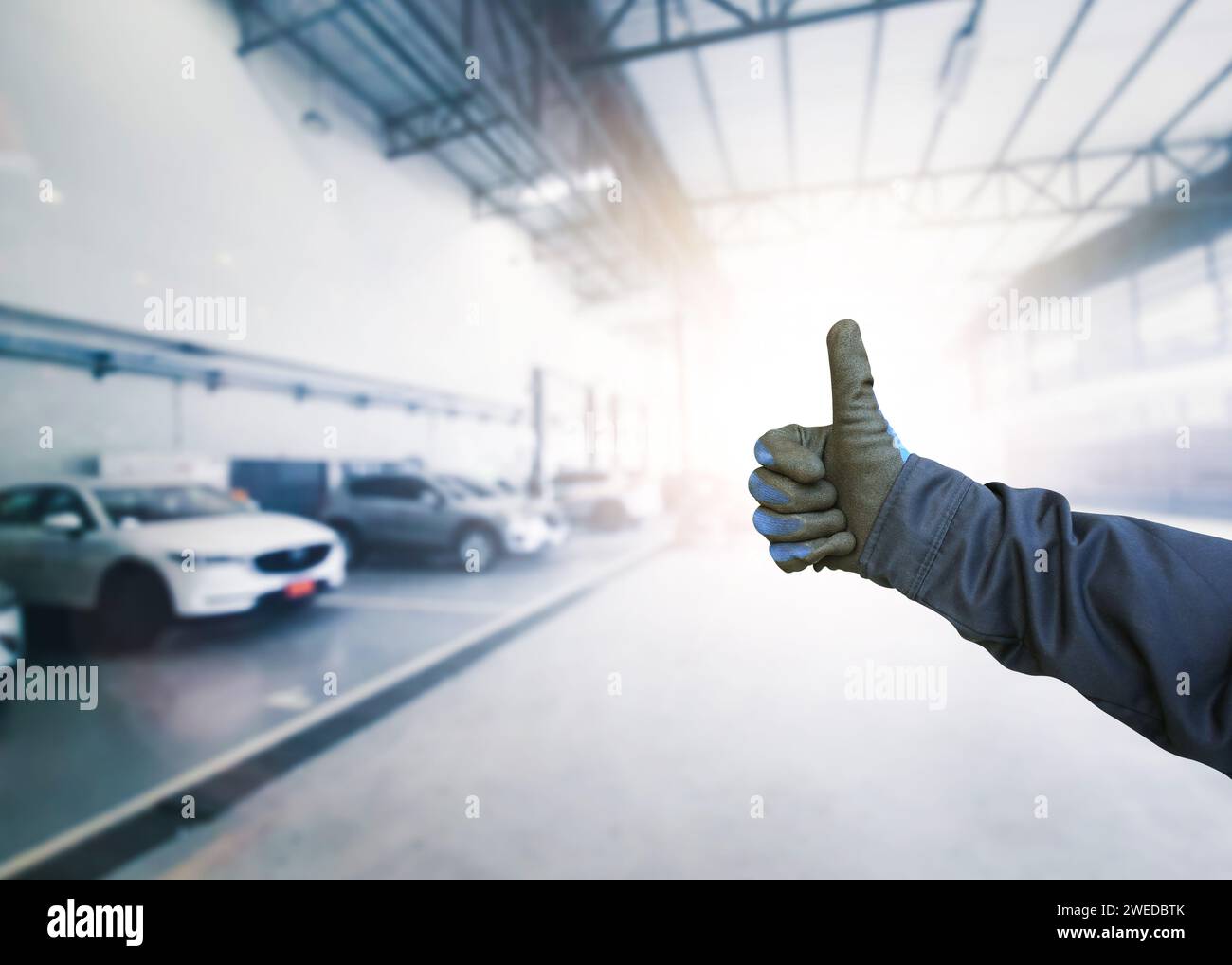 Signalisation mécanique automatique OK avec un geste confiant des pouces vers le haut à l'intérieur d'un centre de service d'entretien de voiture , concept d'affaires de service d'entretien de voiture Banque D'Images