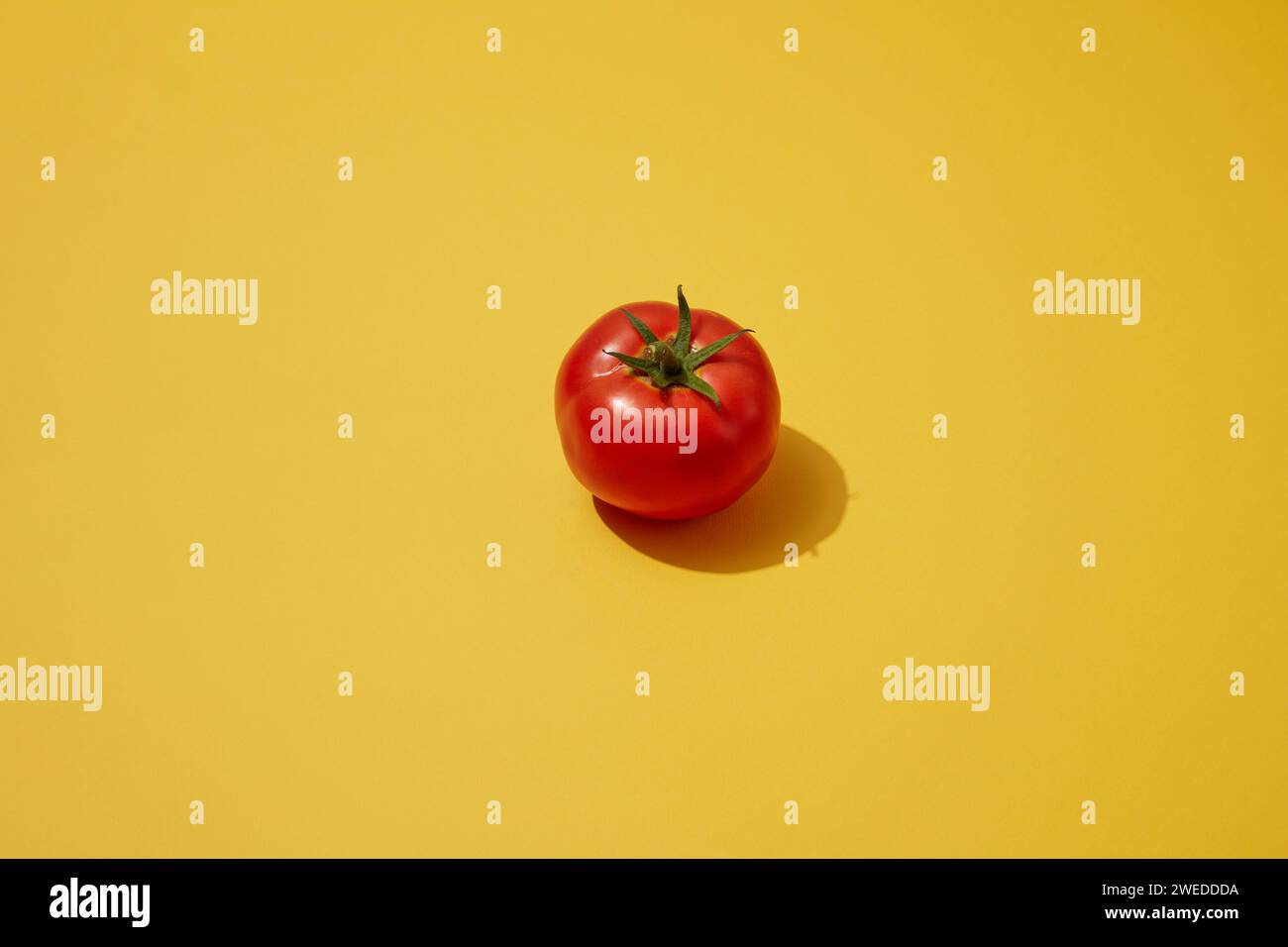 Une tomate isolée sur fond jaune. Tomate (Solanum lycopersicum) est plein d'enzymes qui les rendent grands comme exfoliation qui aide à obtenir Banque D'Images