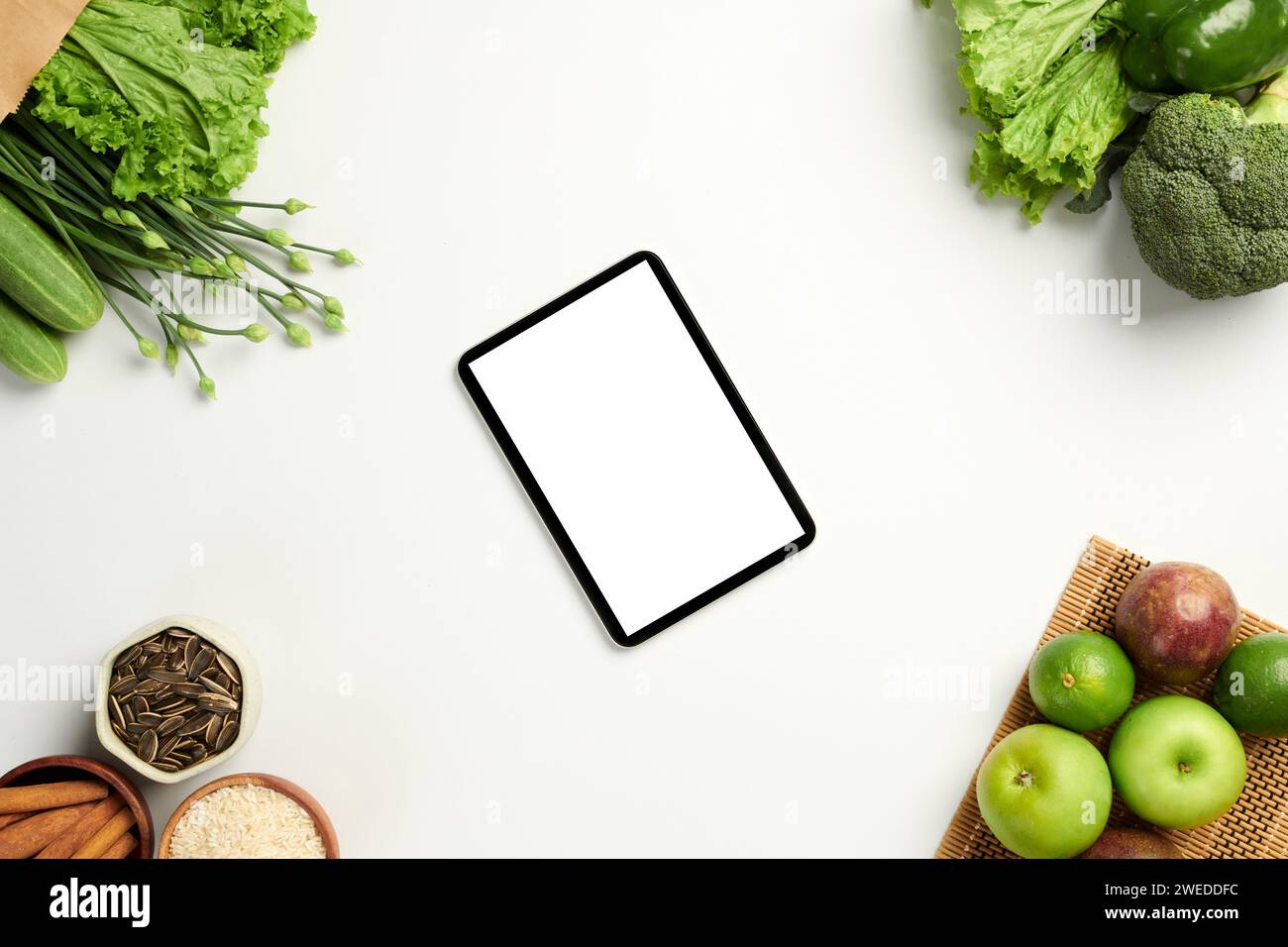 Tablette numérique avec écran blanc sur table avec fruits et légumes frais Banque D'Images