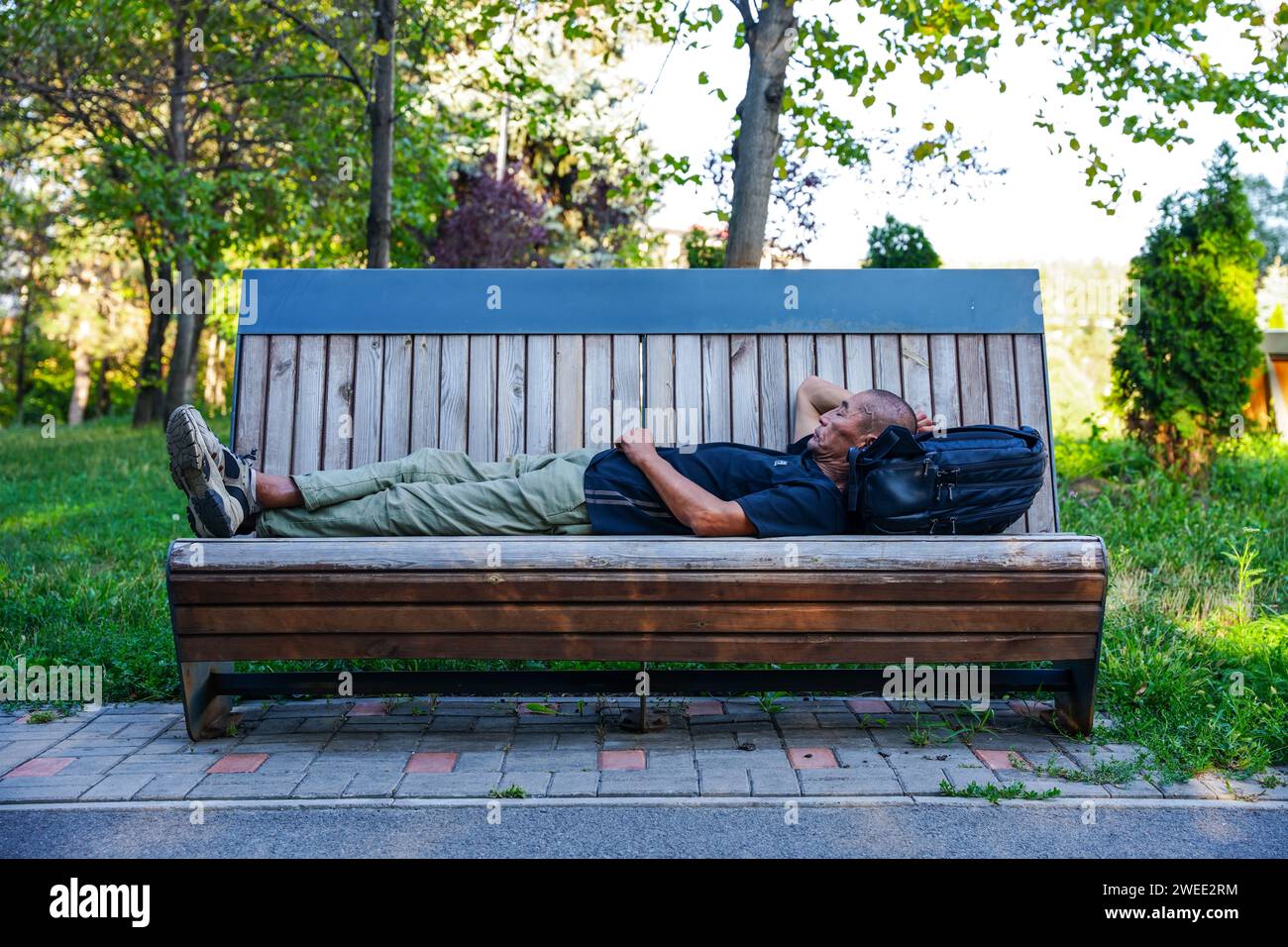 Almaty, Kazakhstan - 17 août 2023 : un asiatique dort sur un banc dans le parc. Banque D'Images