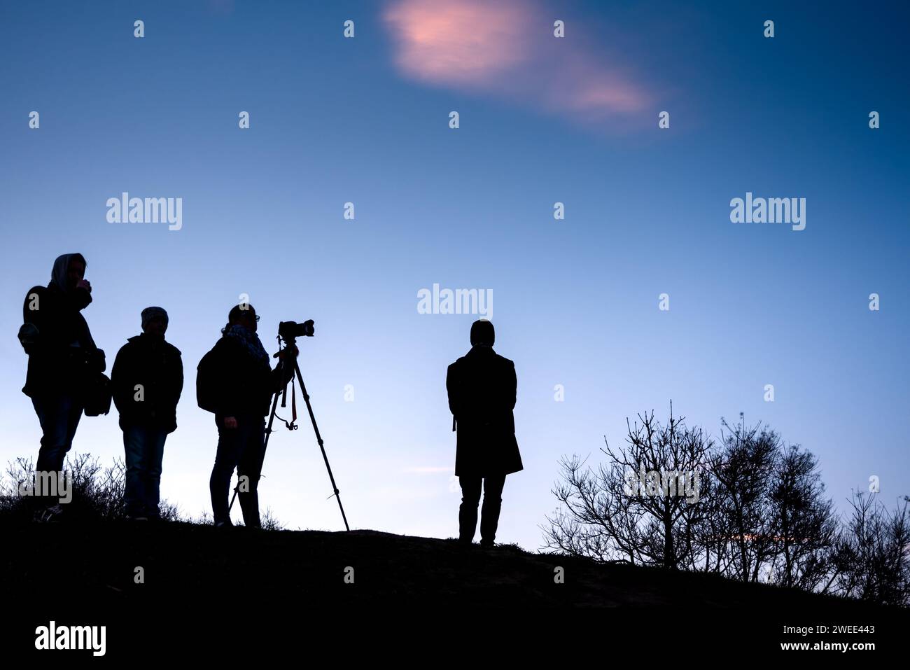 Silhouette d'un groupe de personnes regardant le coucher du soleil sur une colline Banque D'Images
