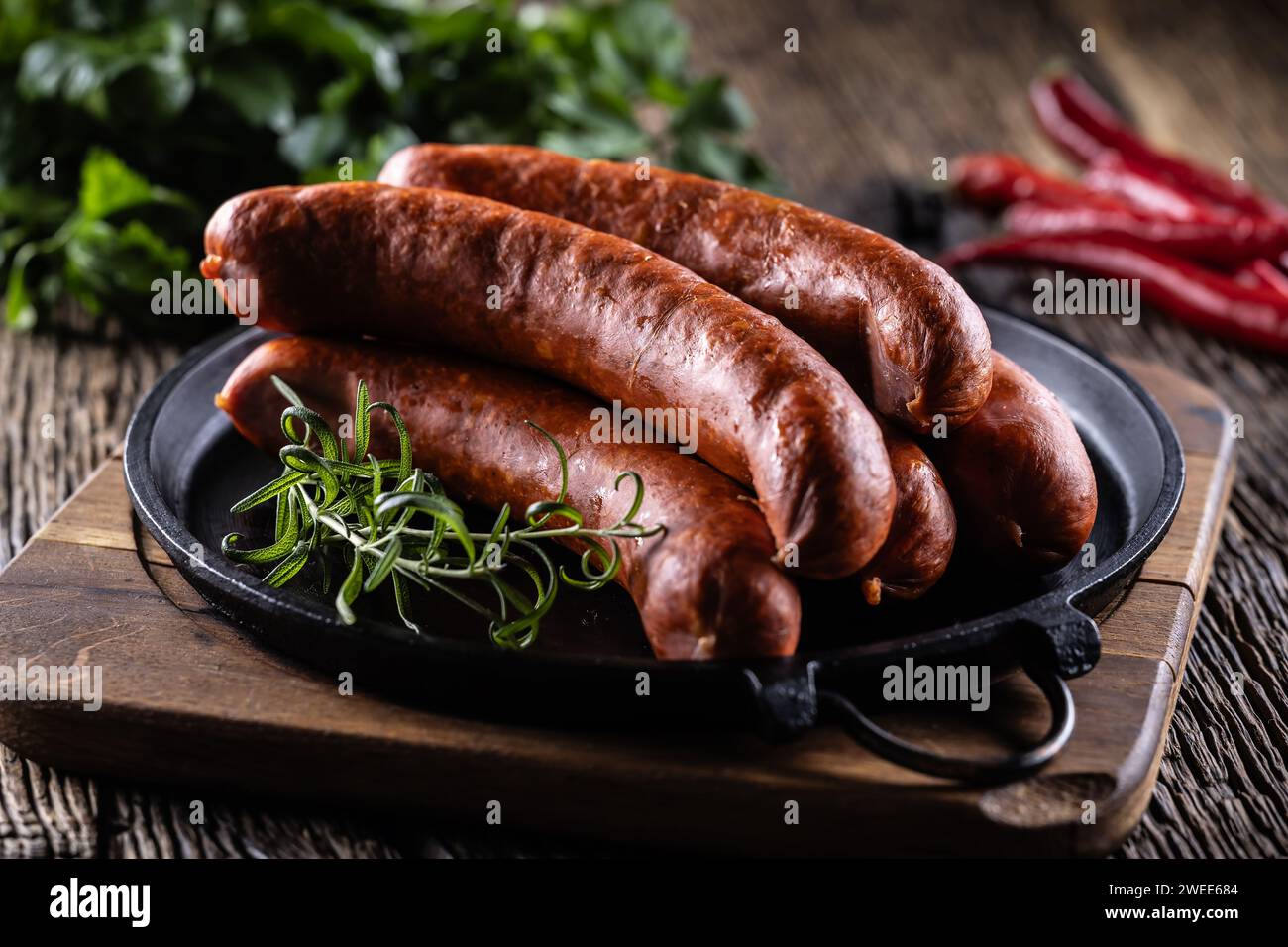 Saucisses fumées de porc au poivre avec du romarin dans une poêle en fonte. Banque D'Images
