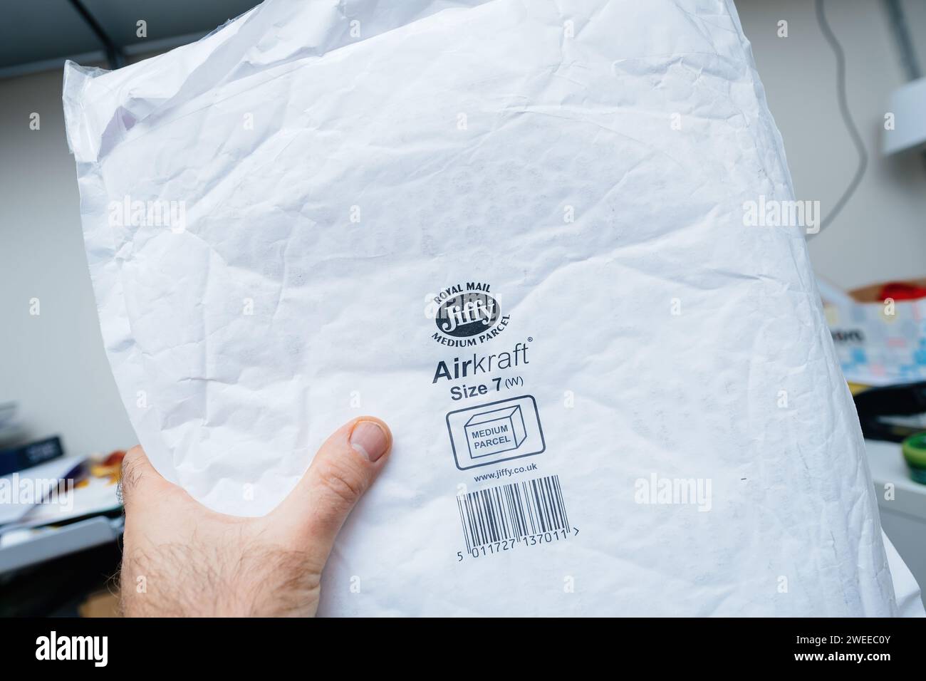 Brême, Allemagne - 28 décembre 2023 : une main masculine tient une enveloppe avec le logo Royal Mail et le texte « Medium Parcel - Air Kraft protection Bubbles », utile pour les colis Medium envoyés Banque D'Images