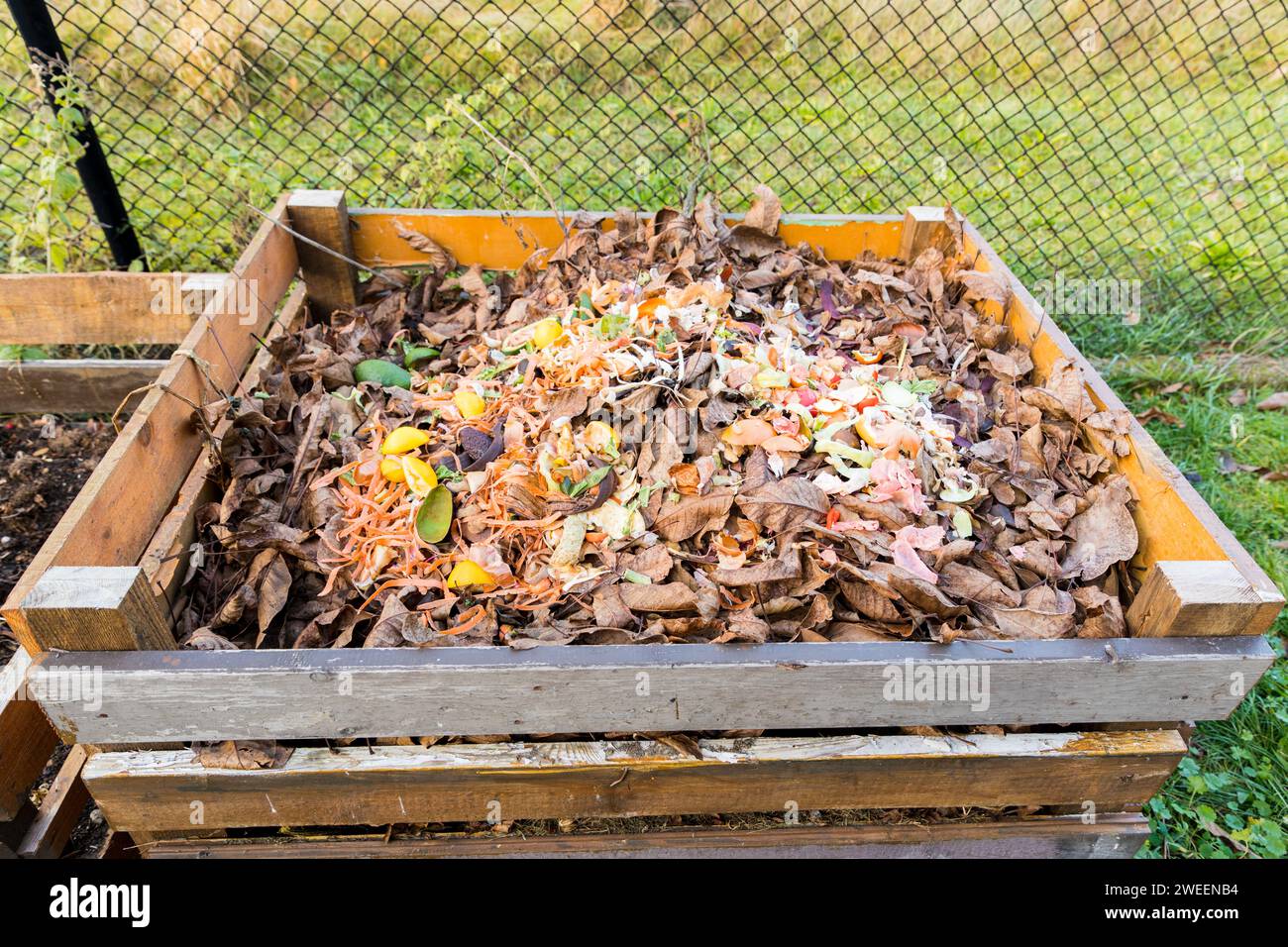 Un composteur fait de planches de bois remplies de bio-déchets de la cuisine. Banque D'Images