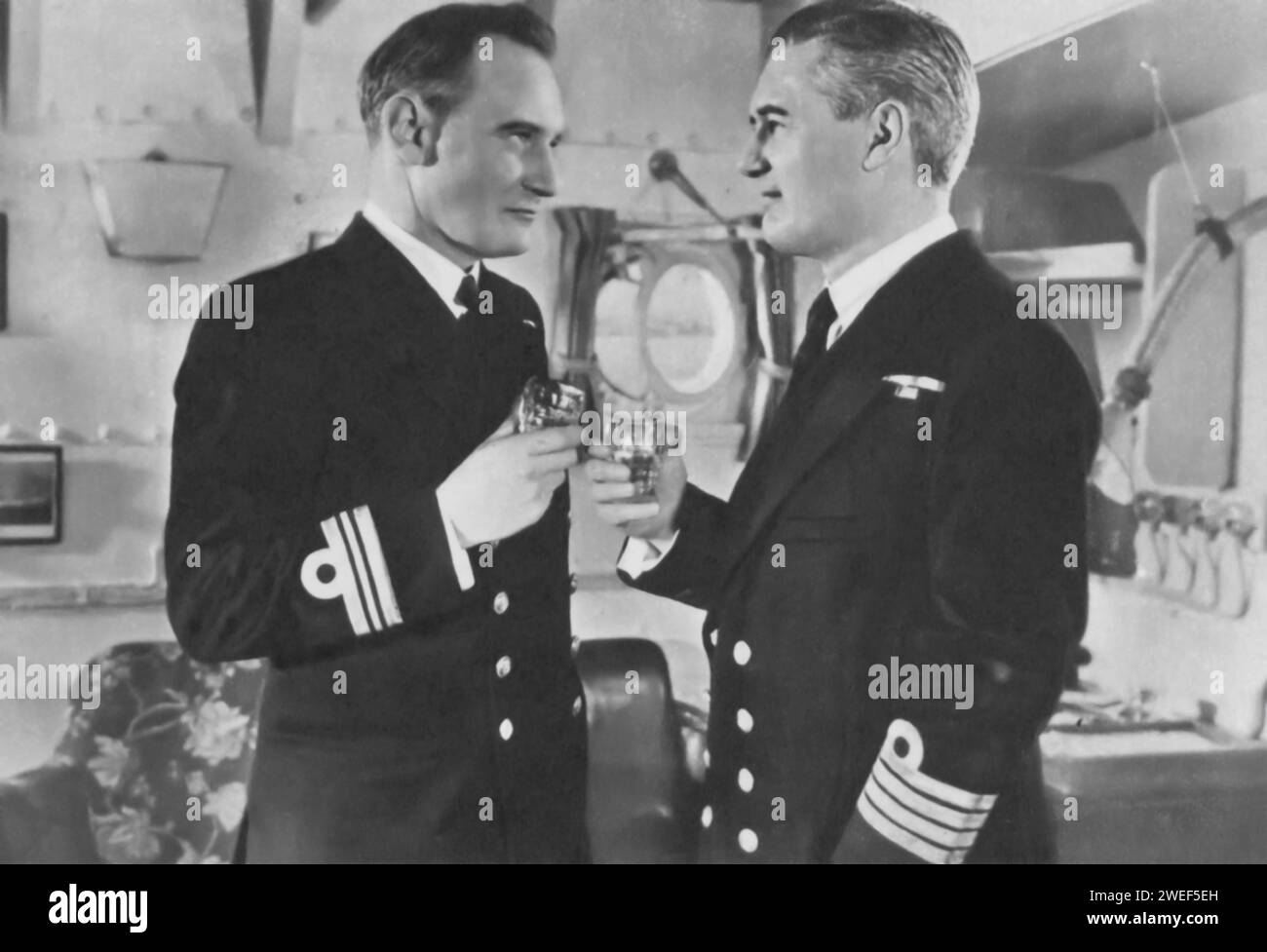 Hugh Williams et Trevor Howard jouent dans 'The Gift Horse' (1952), également connu sous le nom de 'Glory at Sea', un film de guerre britannique. Williams joue le capitaine Randall, un officier de marine expérimenté, et Howard dépeint le lieutenant-commandant Hugh Alginon Fraser, un chef dévoué et compétent. Le film suit l'histoire d'un navire vieillissant de la Seconde Guerre mondiale, le H.M.S. Ballantrae, et de son équipage, alors qu'ils se lancent dans des missions dangereuses et font face aux défis de la guerre en mer. Banque D'Images