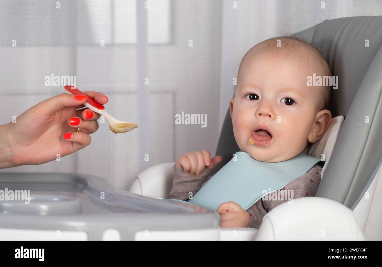 Une mère donne de la bouillie à partir d'une cuillère à un petit garçon de 8 mois. Nourrir les nourrissons. Gros plan Banque D'Images