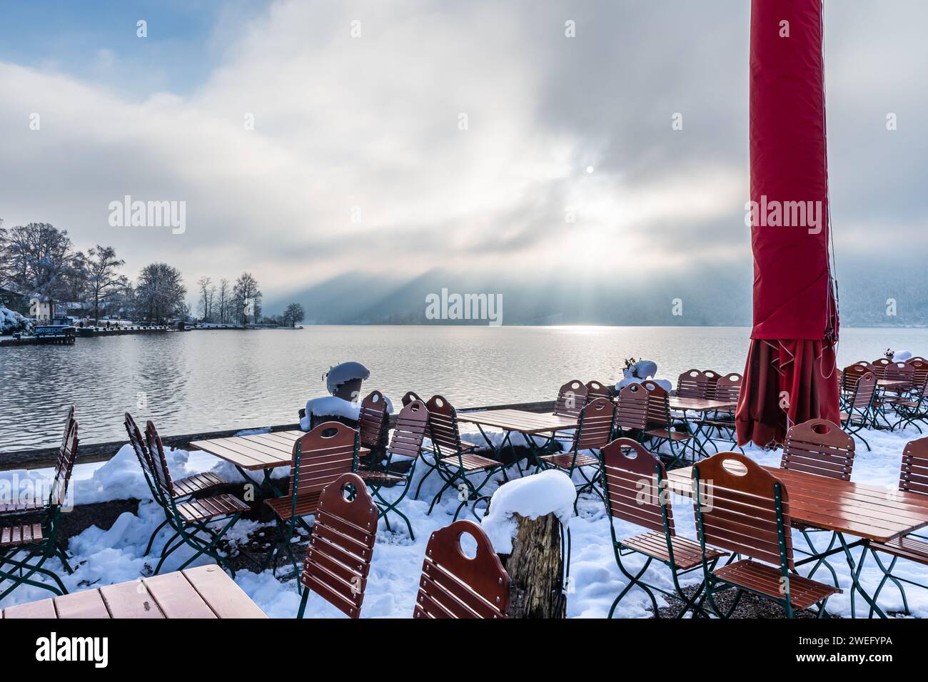 Tables et chaises enneigées d'un café sur la rive du lac Schliersee dans les Alpes allemandes, espace copie Banque D'Images