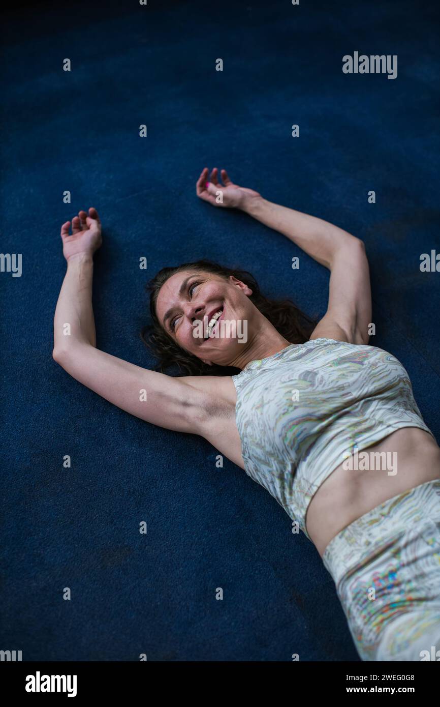 femme souriant en s'allongeant sur le sol Banque D'Images